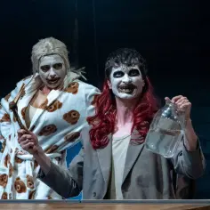 Dwie postacie w makijażu, jedna w szlafroku w misie, druga z butelką. Scena z "Ubu Król".