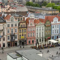 Kolorowe kamienice na rynku, jak ze snu o poznaniu. Ludzie spacerują, siedzą w ogródkach kawiarnianych.