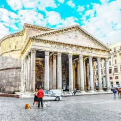 Panteon w Rzymie, niegdyś świątynia wszystkich bogów rzymskich, dziś zachwyca architekturą. Na placu spacerują ludzie i psy.