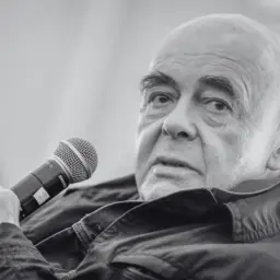 Stanisław Tym, znany z kultowych filmów, trzyma mikrofon.