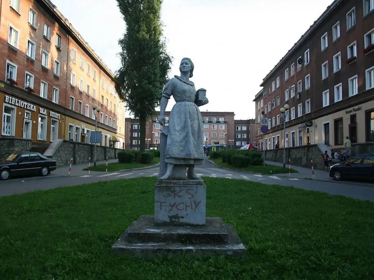 Pomnik kobiety, symbol socrealizmu, stoi przed blokami z wielkiej płyty. To pytanie: socrealizm co to?