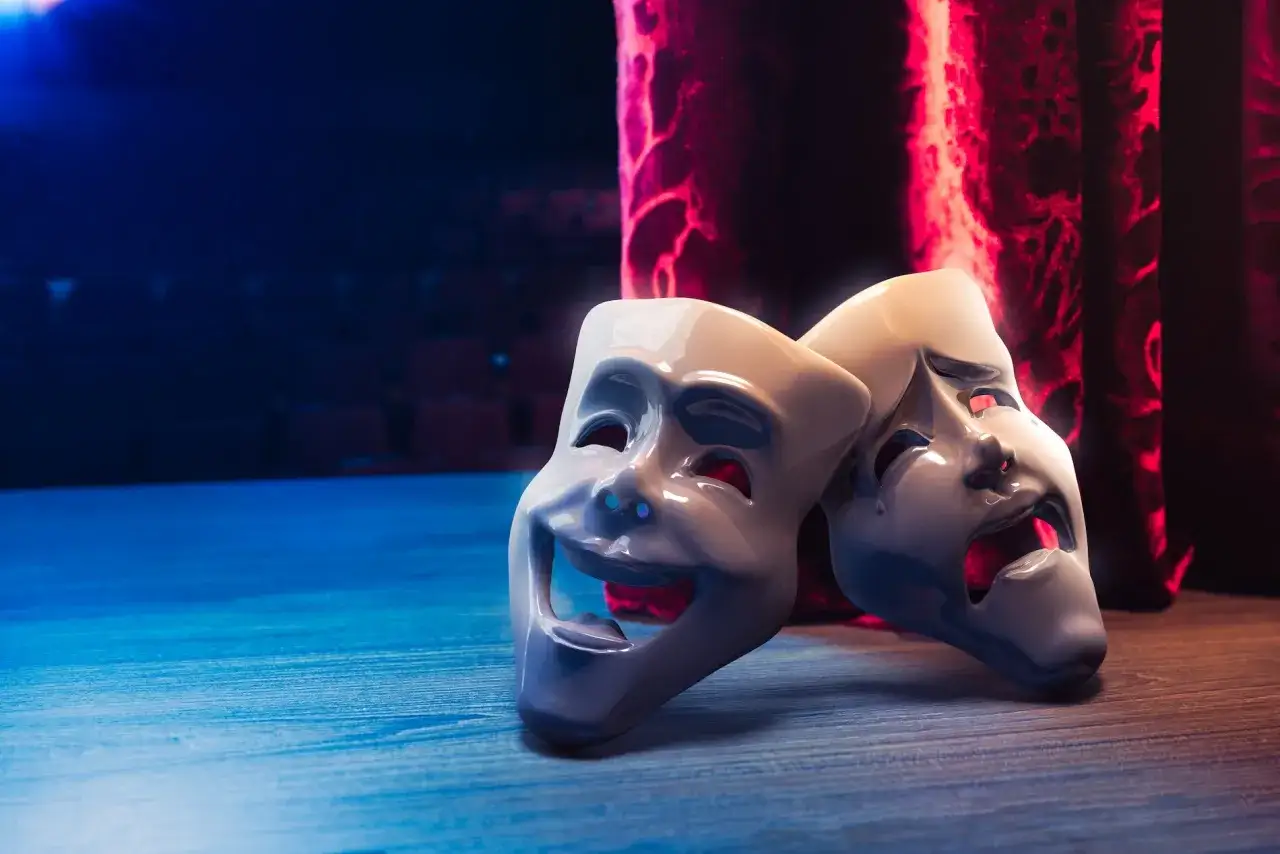 Dwie maski teatralne, jedna uśmiechnięta, druga płacząca, symbolizują zdrada i emocje na scenie życia.
