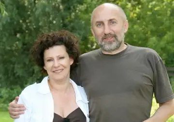 Dorota Kołak z pierwszym mężem, uśmiechnięci, na tle zieleni.